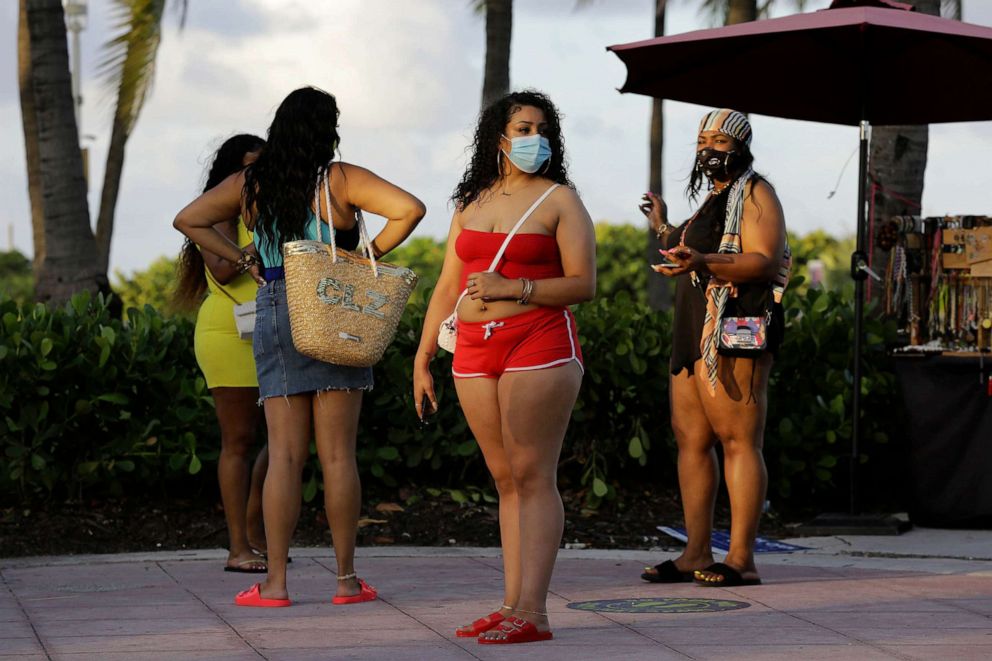 PHOTO: Women wearing protective face masks walk along Ocean Drive amid the coronavirus pandemic, July 24, 2020, in Miami Beach, Fla.