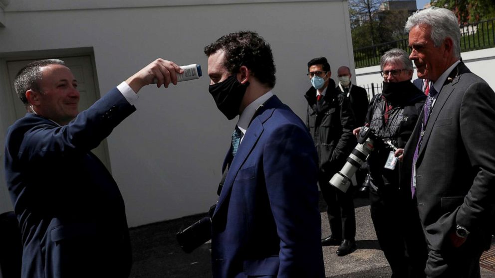 PHOTO: Members of the White House press corps get their temperatures taken by a White House staff member before entering the South Lawn to cover an event in Washington, April 16, 2020.