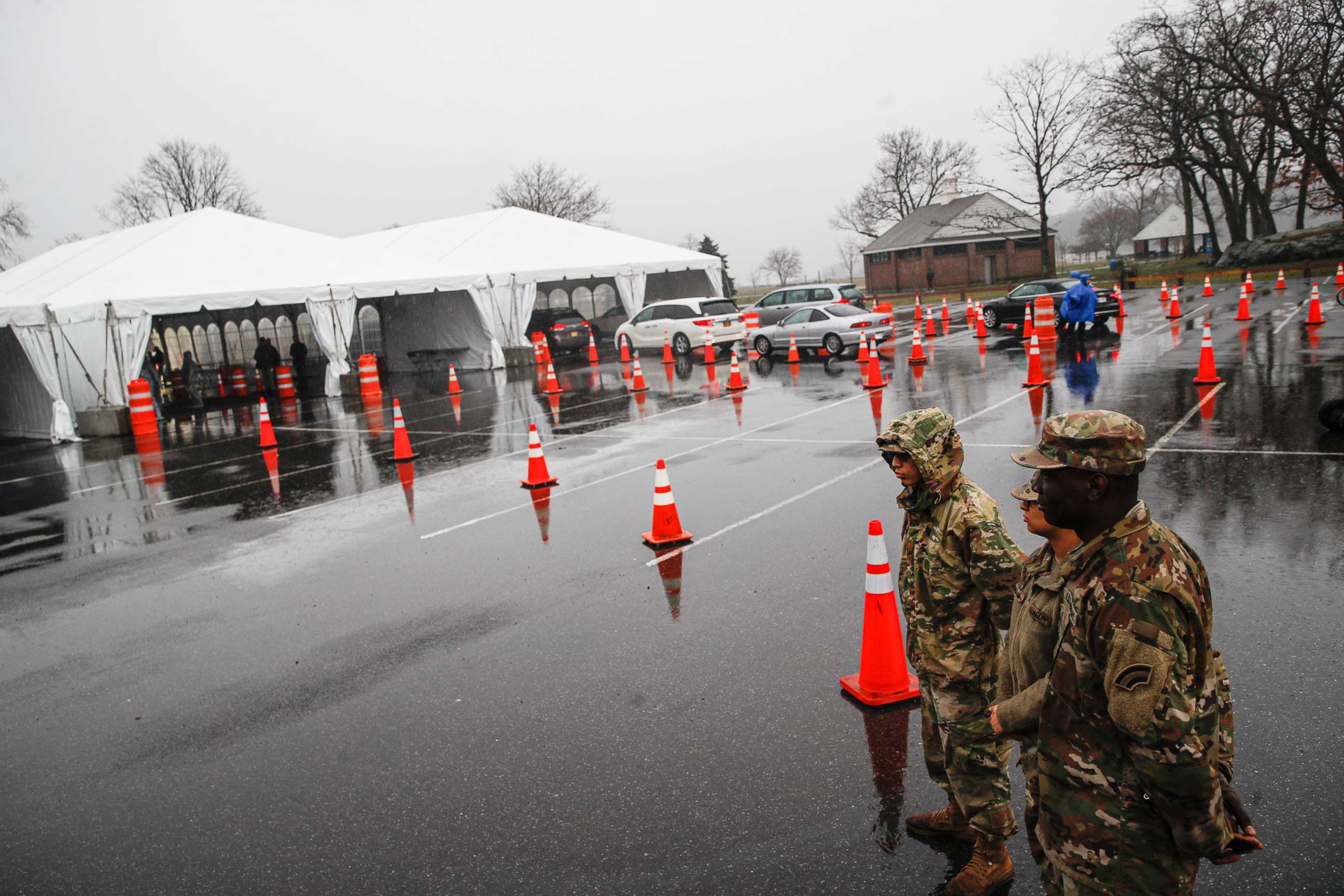 PHOTO: National Guard personnel stand beside a line of motorists waiting for COVID-19 infection testing at Glen Island Park in New Rochelle, New York, on March 13, 2020.