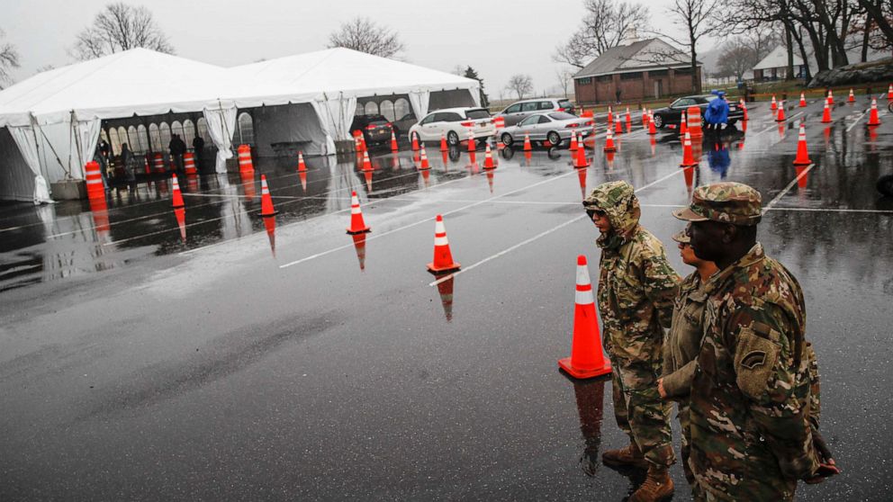 PHOTO: National Guard personnel stand beside a line of motorists waiting for COVID-19 infection testing at Glen Island Park in New Rochelle, New York, on March 13, 2020.