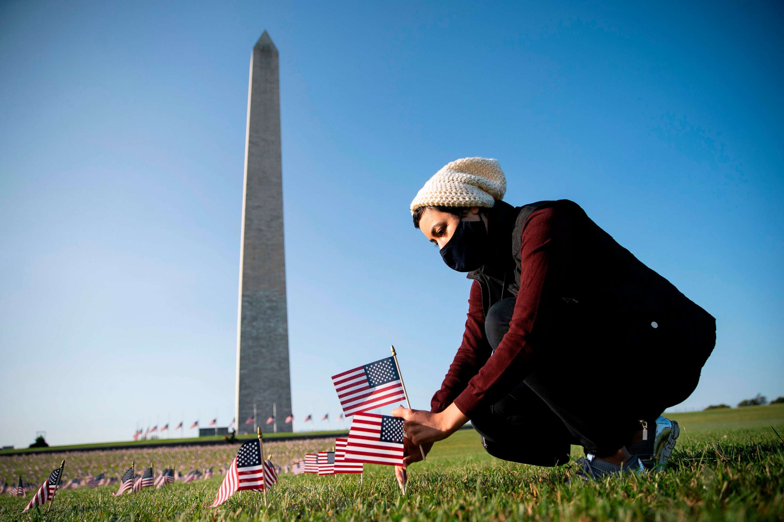PHOTO: A woman places an American flag at a memorial for those who have died from COVID-19 on the National Mall in Washington, D.C., on Sept. 22, 2020.