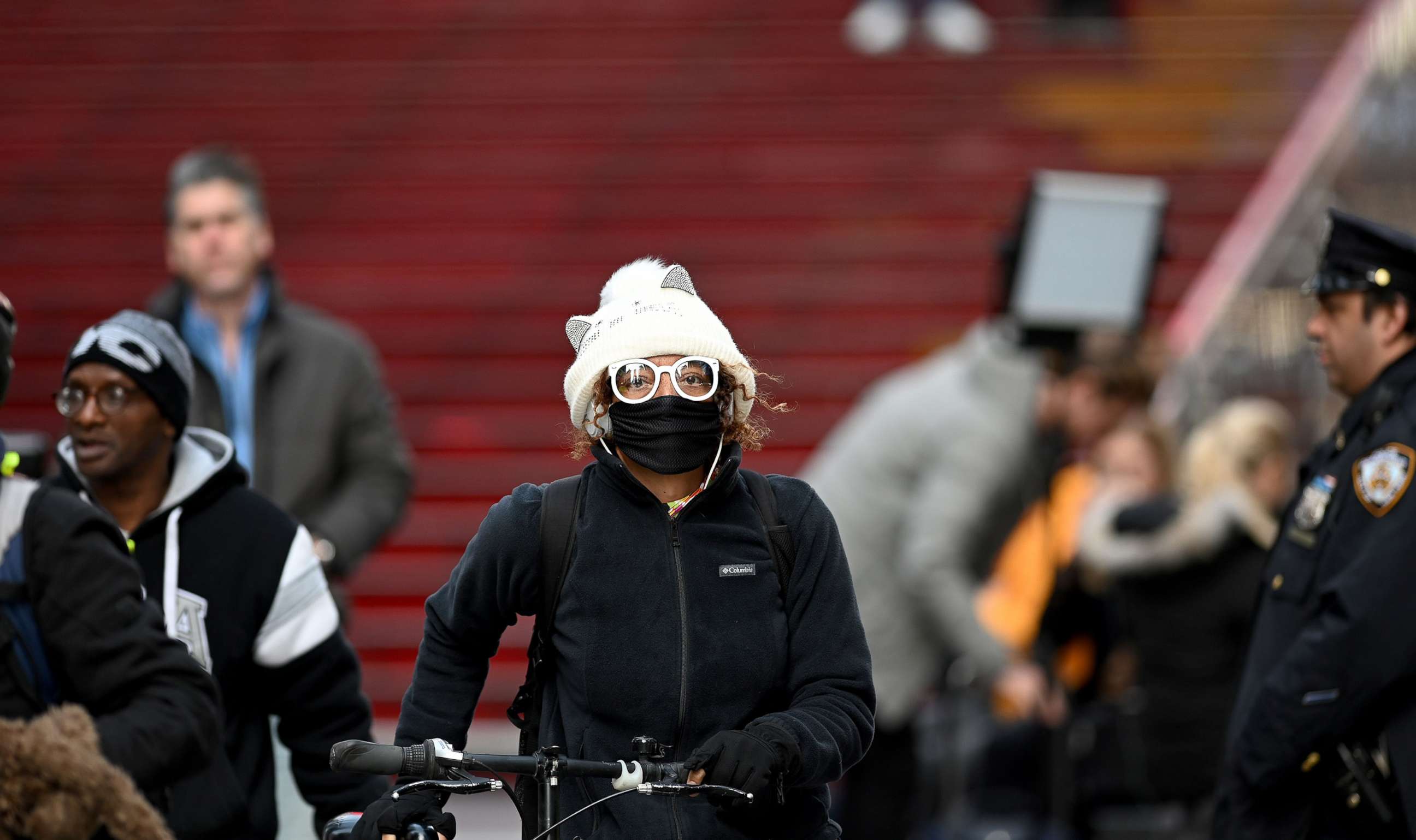 PHOTO: A woman wearing a mask pushes her bike in Times Square, on March 18, 2020 in New York City.