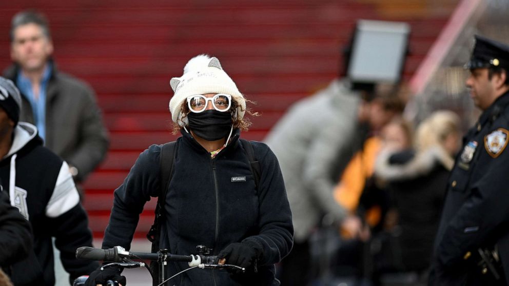 PHOTO: A woman wearing a mask pushes her bike in Times Square, on March 18, 2020 in New York City.