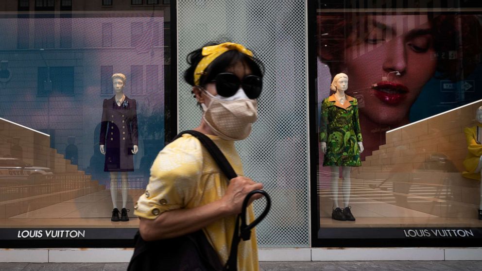 A woman walks pass a Louis Vuitton advertisement in a shopping