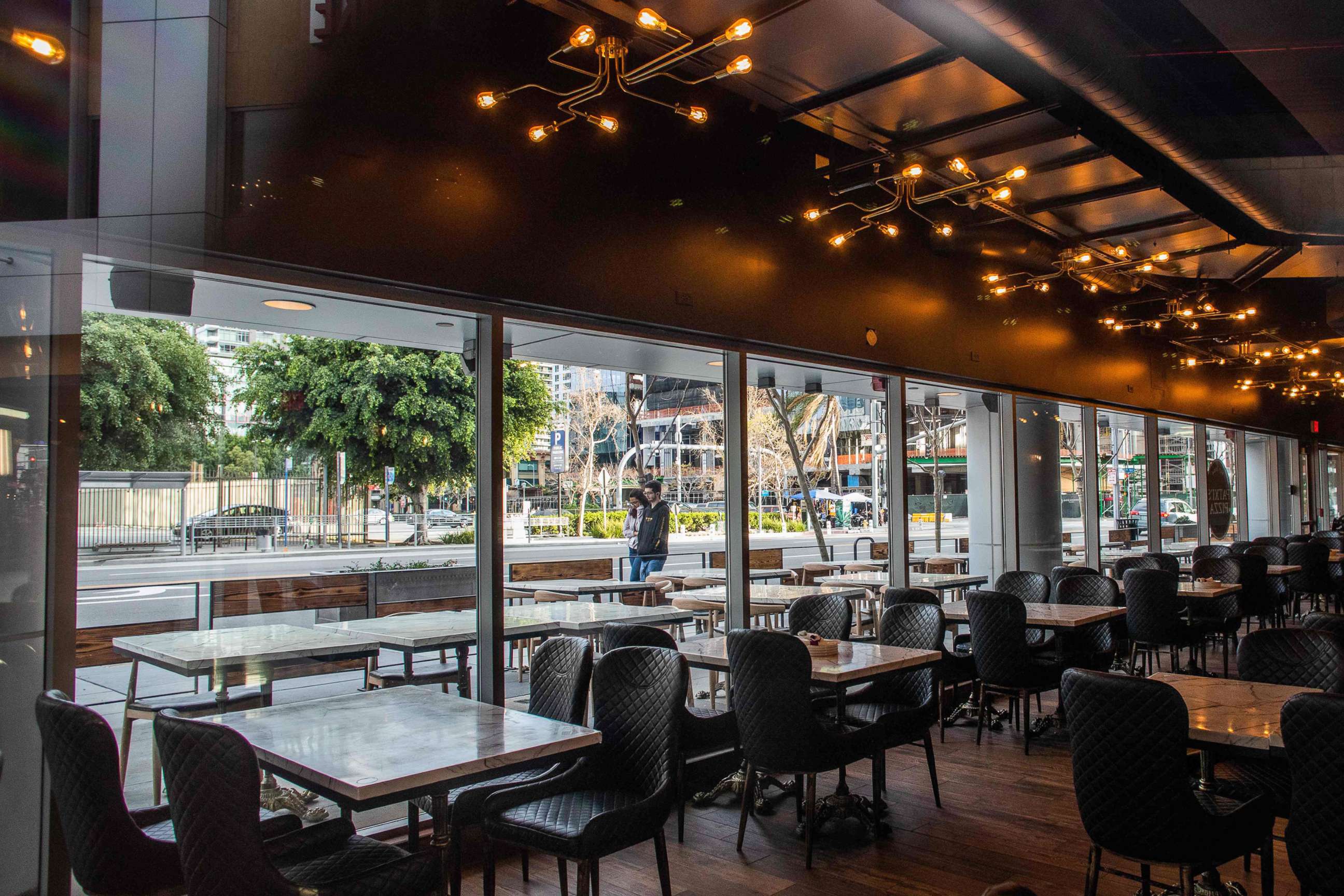 PHOTO: People walk by a closed restaurant in downtown Los Angeles, March 15, 2020.