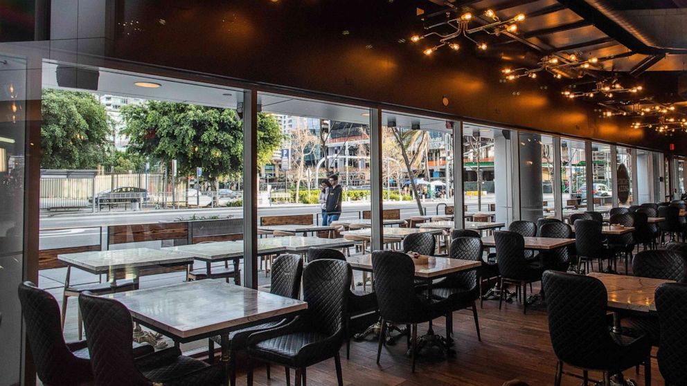 PHOTO: People walk by a closed restaurant in downtown Los Angeles, March 15, 2020.