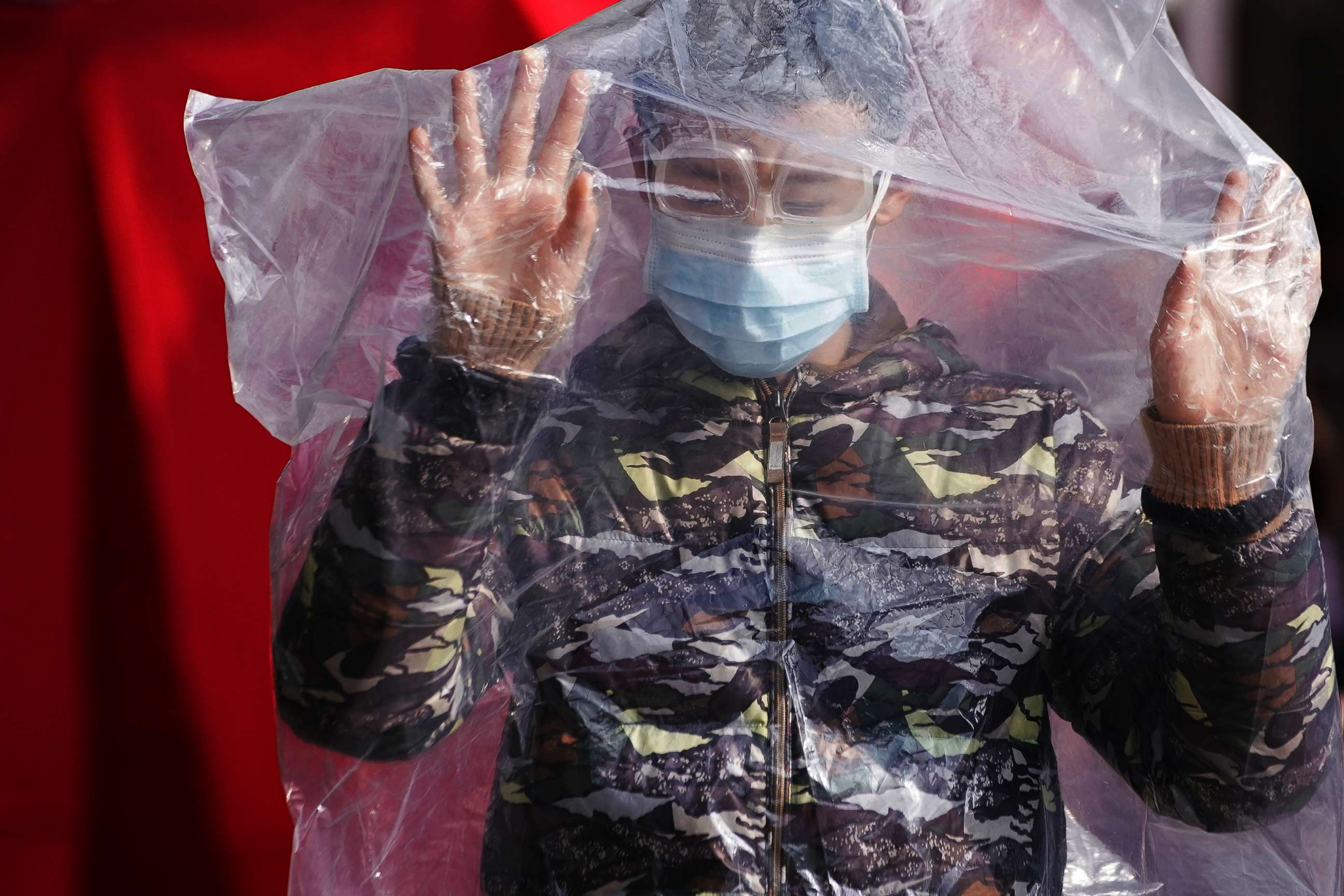 PHOTO: A passenger wearing a mask and covered with a plastic bag walks outside the Shanghai railway station in Shanghai, as the country is hit by an outbreak of a new coronavirus, Feb. 9, 2020. 