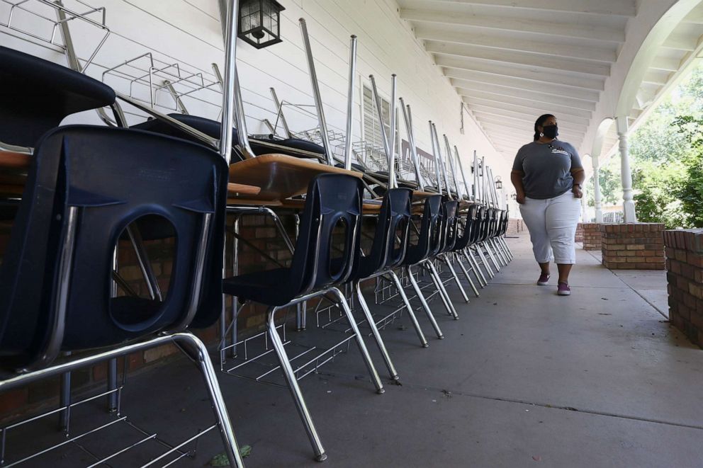 PHOTO: Kristina Washington, special education staff member at Desert Heights Preparatory Academy, walks past a series of desks and chairs at the school, June 1, 2020, in Phoenix.