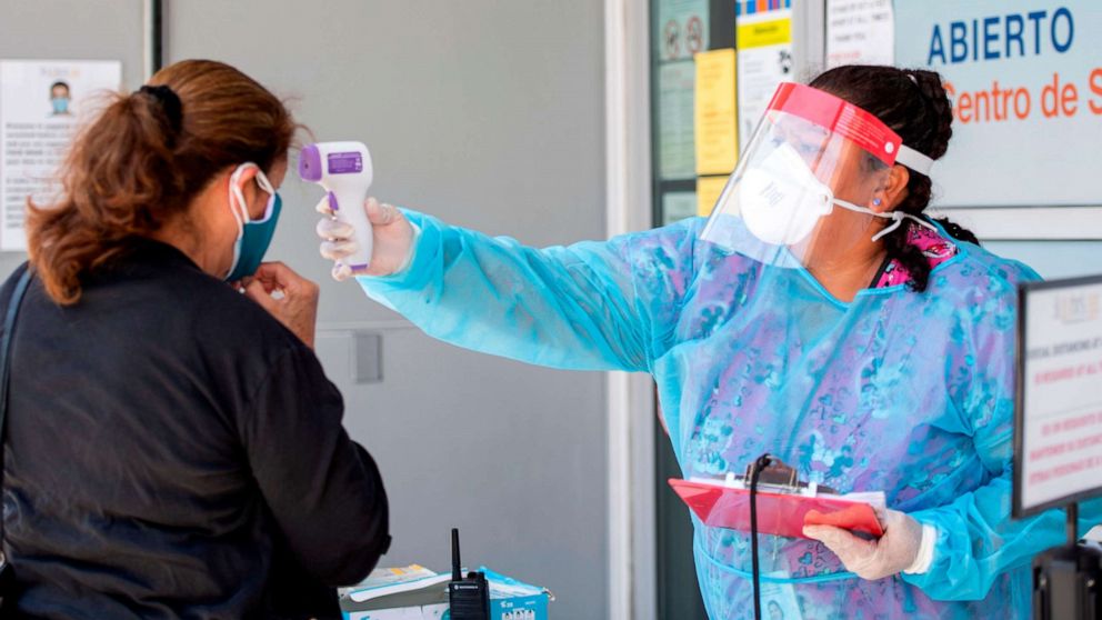 PHOTO: A health worker takes a patient's temperature before sending them to a tent to be tested at a COVID-19 testing site at St. John's Well Child and Family Center, amid the novel coronavirus pandemic, July 24, 2020, in Los Angeles, California.