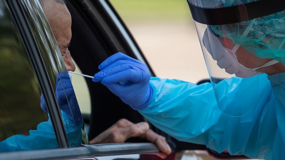 PHOTO: A health care worker uses a swab to test a man for COVID-19 at a drive-in testing location in Houston, Texas, on Aug. 18, 2020.