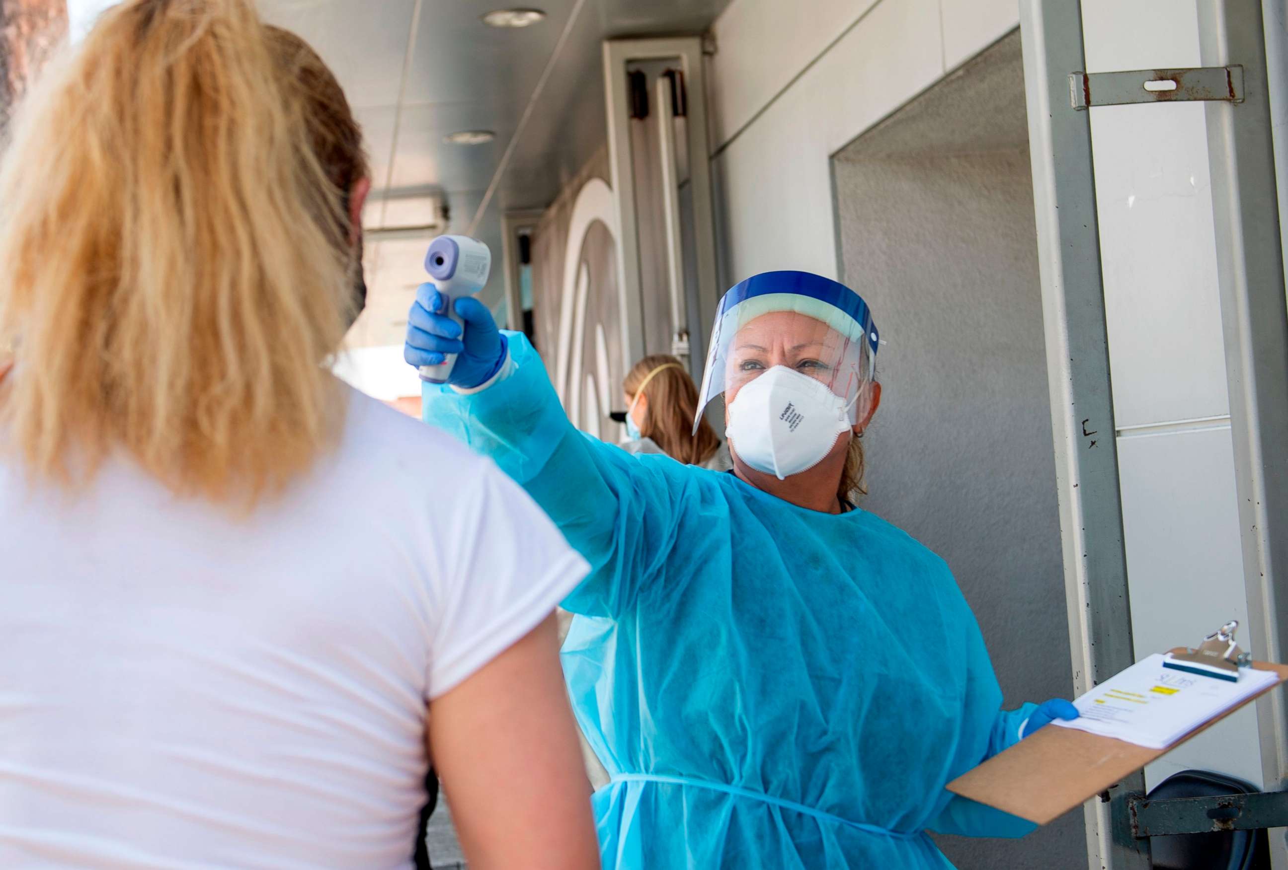 PHOTO: A health worker takes a patient's temperature before sending them to a tent to be tested at a COVID-19 testing site at St. John's Well Child and Family Center in Los Angeles, California, on July 24, 2020.