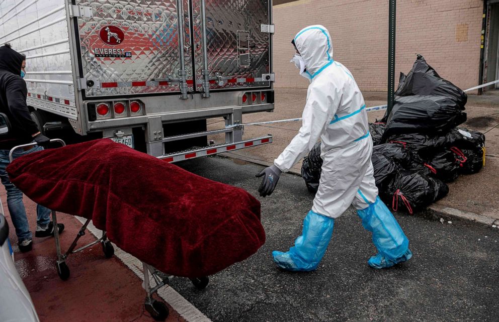 PHOTO: A man in a Hazmat suit transports a deceased body on a stretcher outside a funeral home in Brooklyn on April 30, 2020 in New York City.
