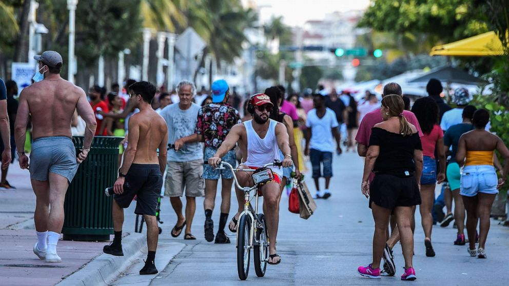 PHOTO: A man rides a bicycle as people walk on Ocean Drive in Miami Beach, Fla. on June 26, 2020.