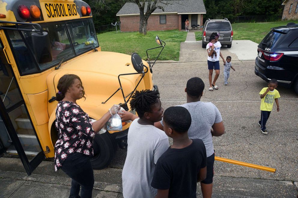 PHOTO: Sheledia Kelly hands food to kids as the Vicksburg Warren School District delivers meals to school aged children in Warren County, Miss., March 18, 2020. 