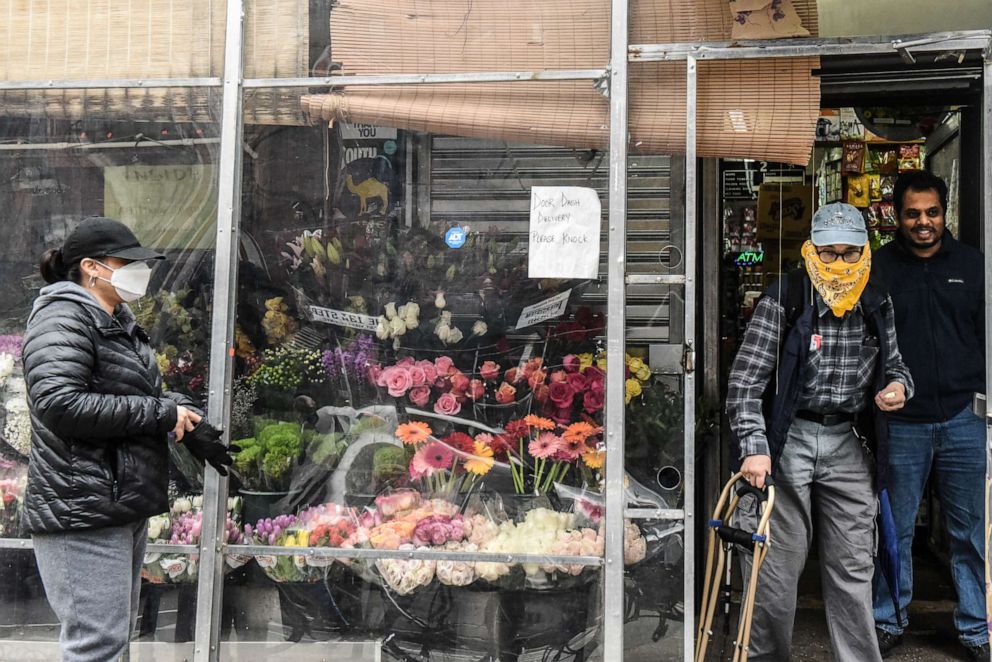 PHOTO: A worker controls the flow of customers through a door in a bodega on April 29, 2020 in New York City.