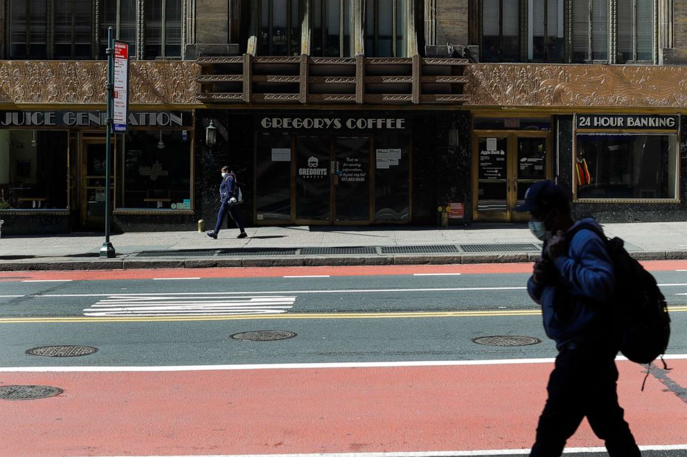 PHOTO: Pedestrians wear protective masks during the coronavirus pandemic as the pass businesses that are closed on 42nd Street, May 15, 2020, N.Y.