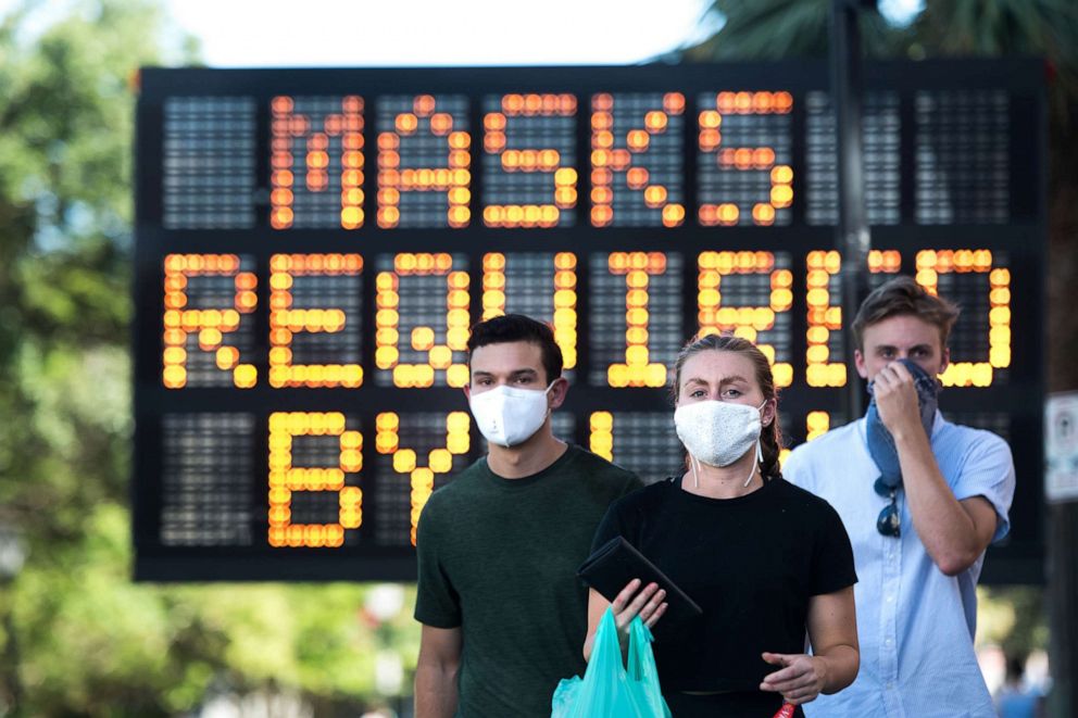 PHOTO: People wear protective face masks walk along King St. on July 18, 2020 in Charleston, S.C.