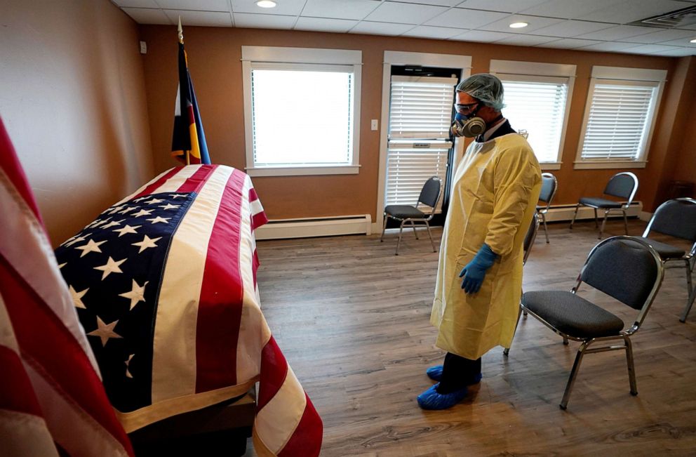 PHOTO: Michael Neel, funeral director of of All Veterans Funeral and Cremation, wearing full PPE, looks at the casket of George Trefren, a 90 year old Korean War veteran who died of the coronavirus disease in a nursing home, in Denver, April 23, 2020.