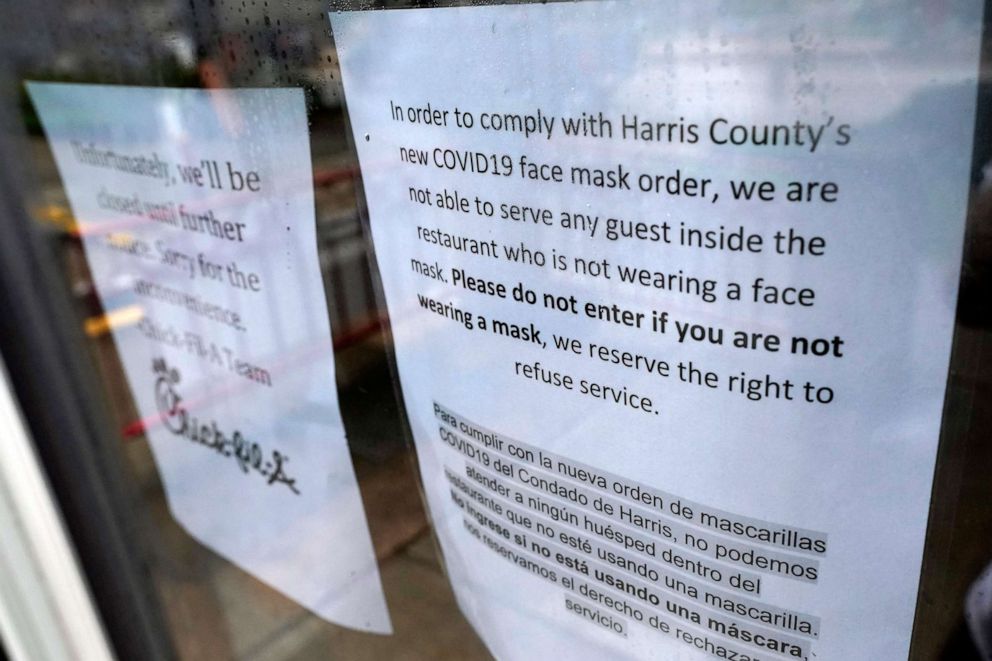 PHOTO: A sign about the new face mask order is posted on the door of a closed restaurant, June 25, 2020, in Houston.