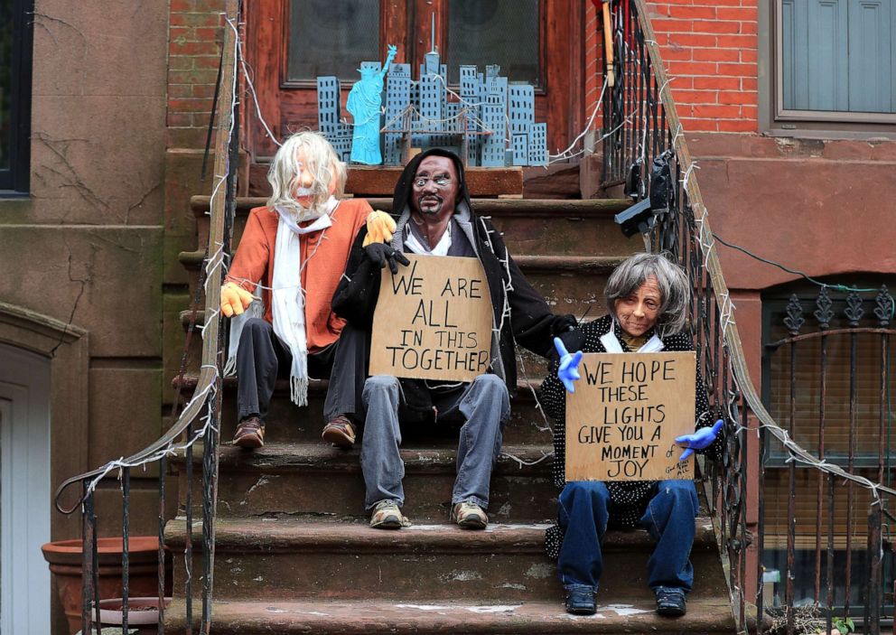 PHOTO: Mannequins sit holding a "We Are All In This Together" sign as part of a display with a model of the NYC skyline and statue of liberty on a stoop on April 23, 2020 in Brooklyn, N.Y.