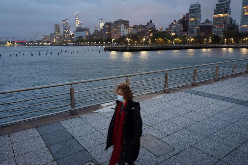 PHOTO: A woman wears a face mask as she walks on Pier 45 in Hudson River Park, April 30, 2020, in New York.