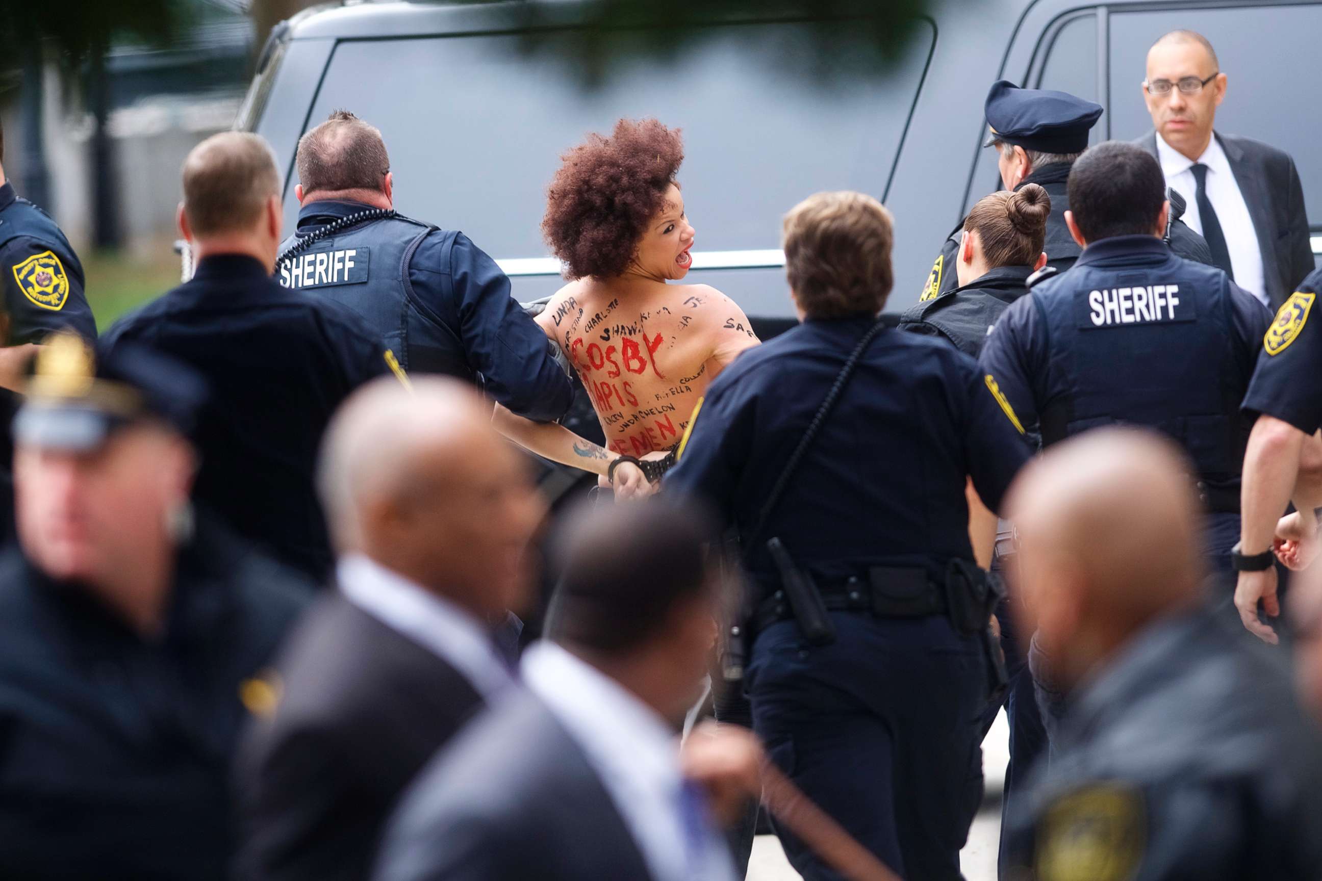 PHOTO: A topless protester wearing body paint is arrested as Bill Cosby arrives at the Montgomery County Courthouse for the first day of his sexual assault retrial on April 9, 2018 in Norristown, Pa.