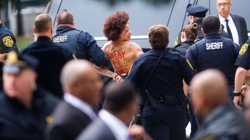 PHOTO: A topless protester wearing body paint is arrested as Bill Cosby arrives at the Montgomery County Courthouse for the first day of his sexual assault retrial on April 9, 2018 in Norristown, Pa.