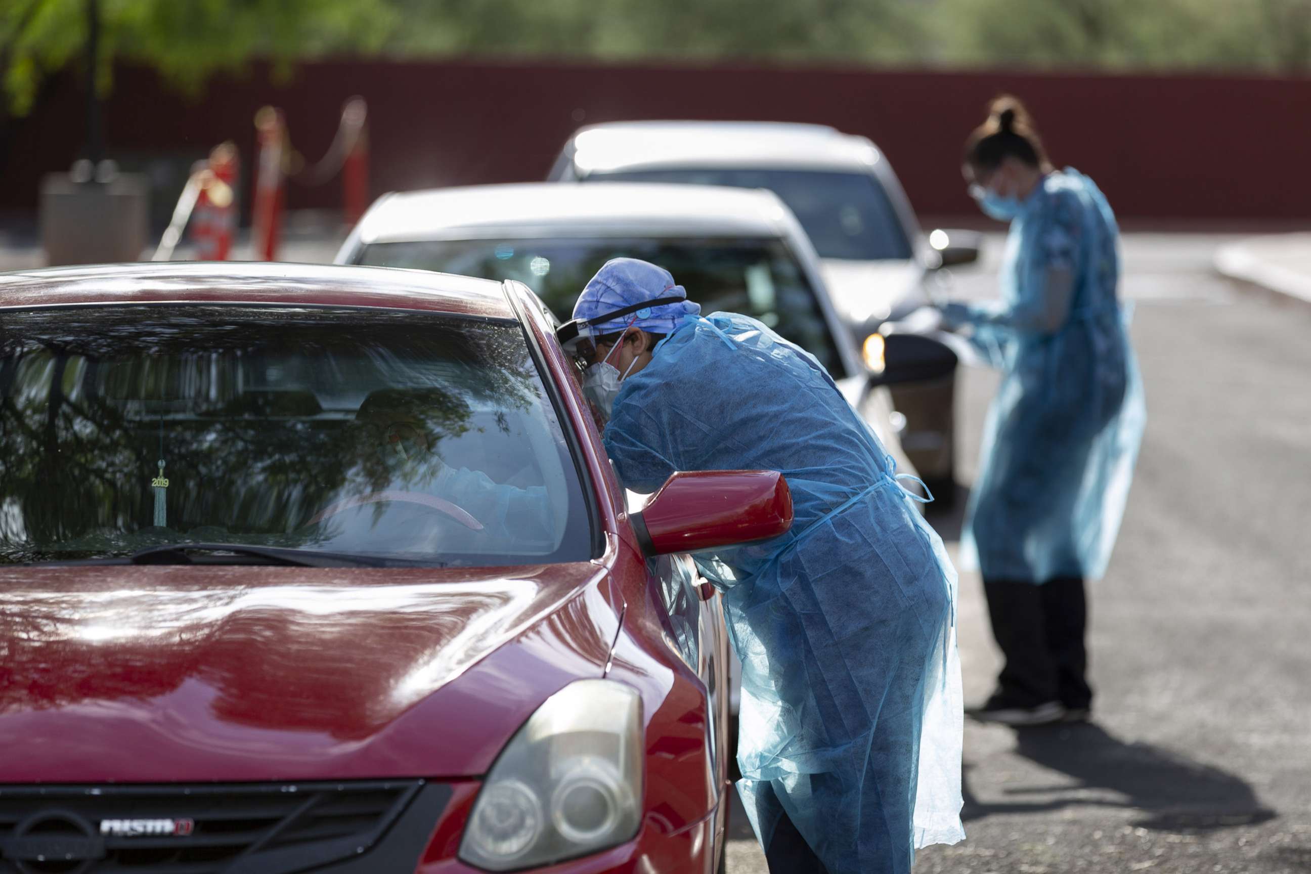 PHOTO: Healthcare workers wearing personal protective equipment (PPE) administer tests at an El Rio Health Covid-19 drive-thru testing site in Tucson, Ariz., July 13, 2020. 
