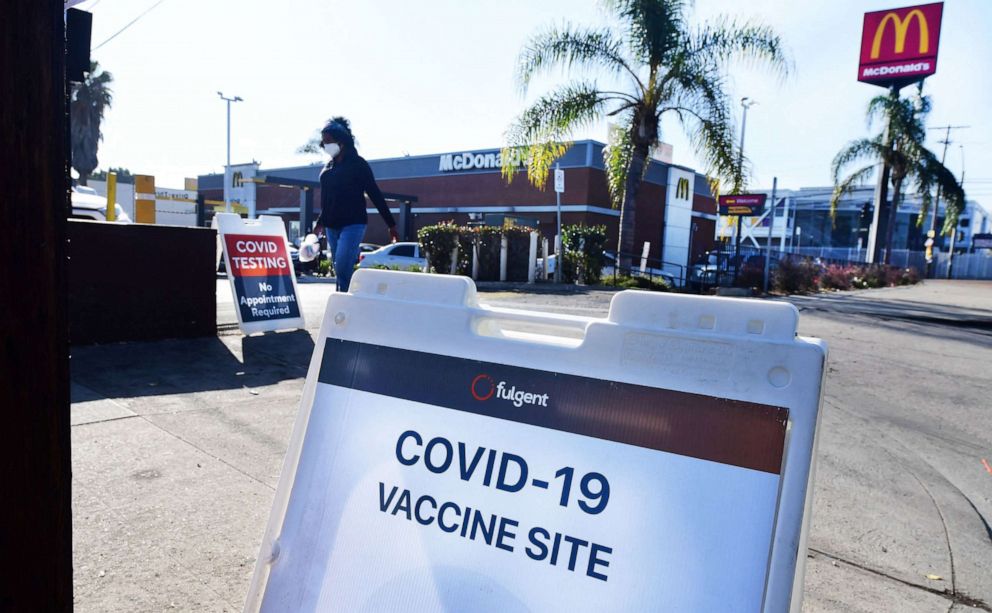 PHOTO: A woman walks past signs for a COVID-19 vaccine mobile clinic hosted by McDonald's and the California Department of the Public Health, Sept. 21, 2021, in Los Angeles.