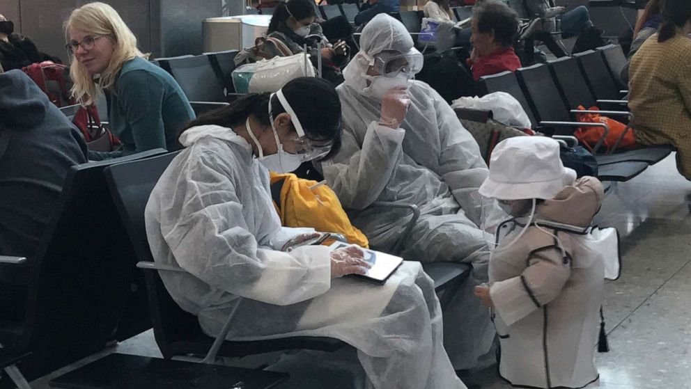 PHOTO: A group of travellers wear protective clothing in the departure lounge at Heathrow Airport Terminal 2 in London, March 19, 2020. 