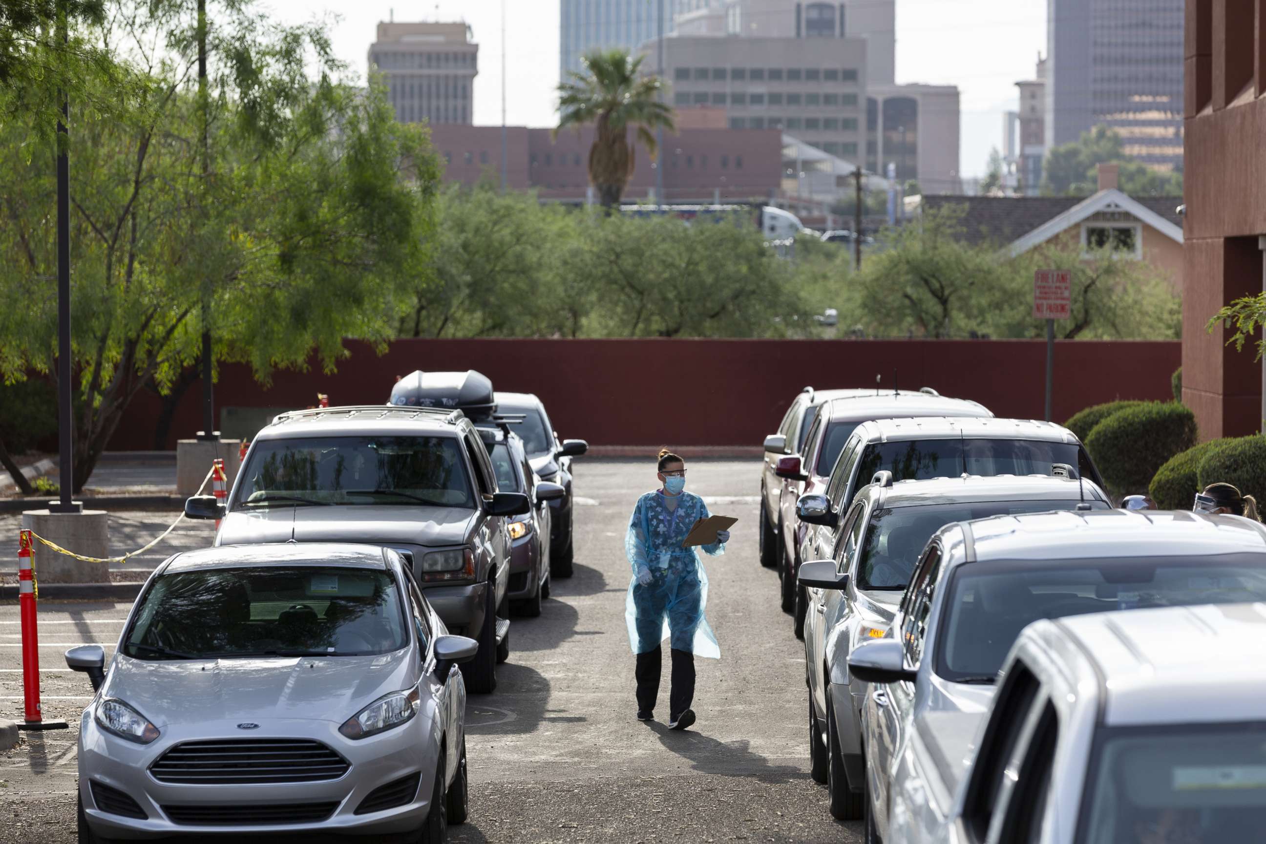 PHOTO: A healthcare worker wearing personal protective equipment (PPE) collects paperwork at an El Rio Health Covid-19 drive-thru testing site in Tucson, Arizona, on July 13, 2020.