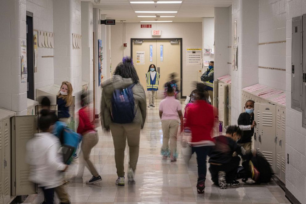 PHOTO: A child acting as hallway monitor watches as children move about a hallway wearing COVID-19 protective masks at Carter Traditional Elementary School in Louisville, Ky., Jan. 24, 2022.