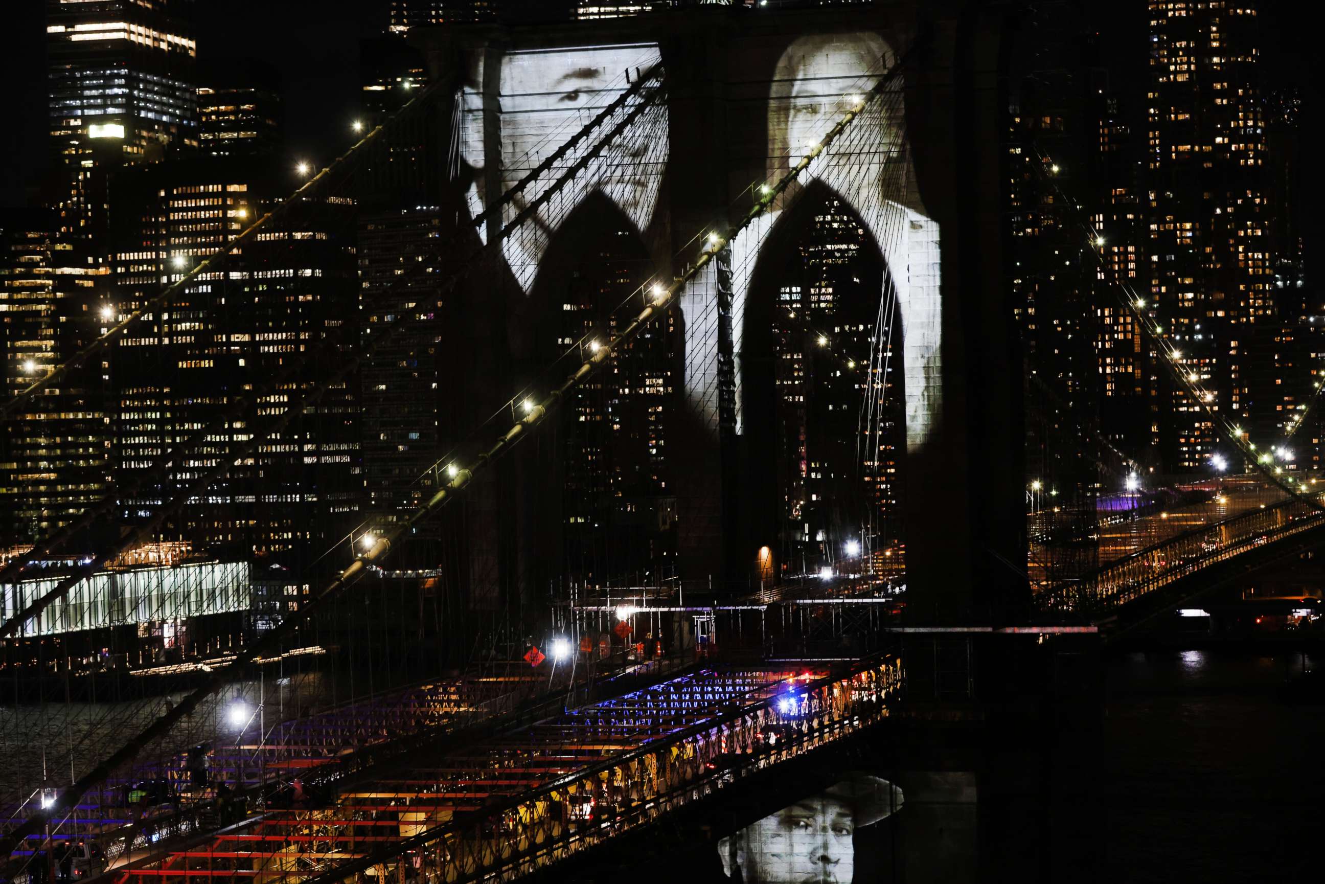 PHOTO: Faces of victims of COVID-19 are projected onto the Brooklyn Bridge during a memorial service called "A COVID-19 Day of Remembrance" on March 14, 2021 in New York City.