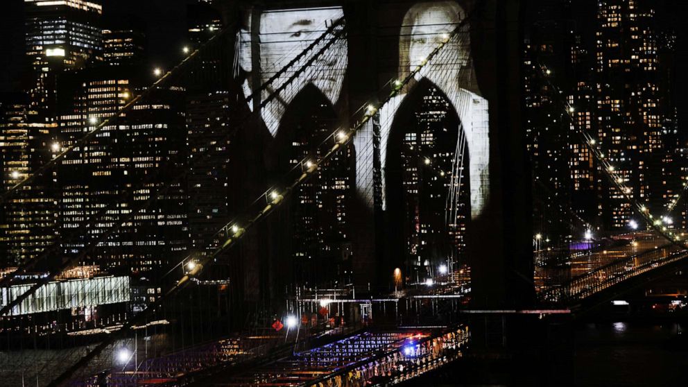 PHOTO: Faces of victims of COVID-19 are projected onto the Brooklyn Bridge during a memorial service called "A COVID-19 Day of Remembrance" on March 14, 2021 in New York City.