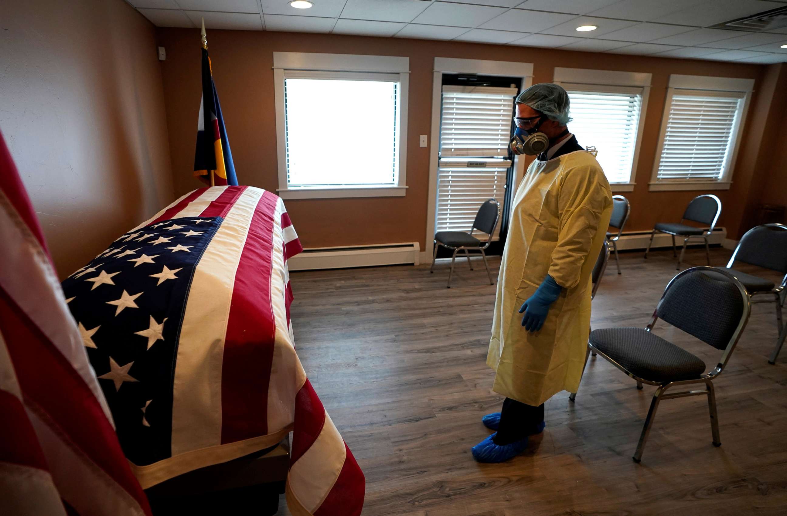PHOTO: Michael Neel, funeral director of of All Veterans Funeral and Cremation, wearing full PPE, looks at the U.S. flag on the casket of George Trefren, a 90 year old Korean War veteran who died of COVID-19 in a nursing home, in Denver, April 23, 2020.