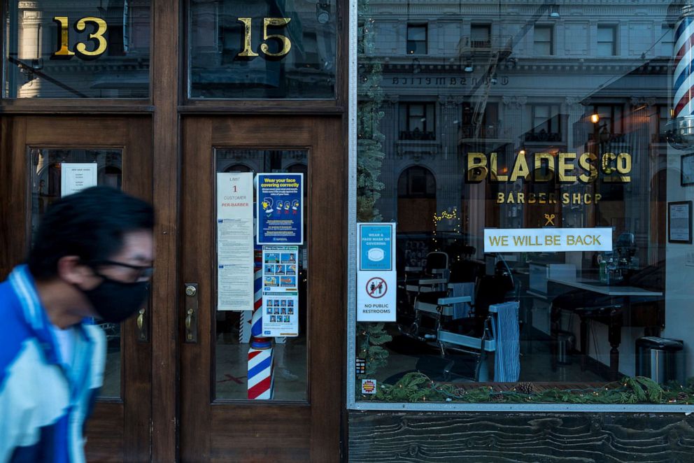PHOTO: A pedestrian wearing a protective mask walks past a temporarily closed barber shop in San Francisco, Calif., Dec. 8, 2020. 