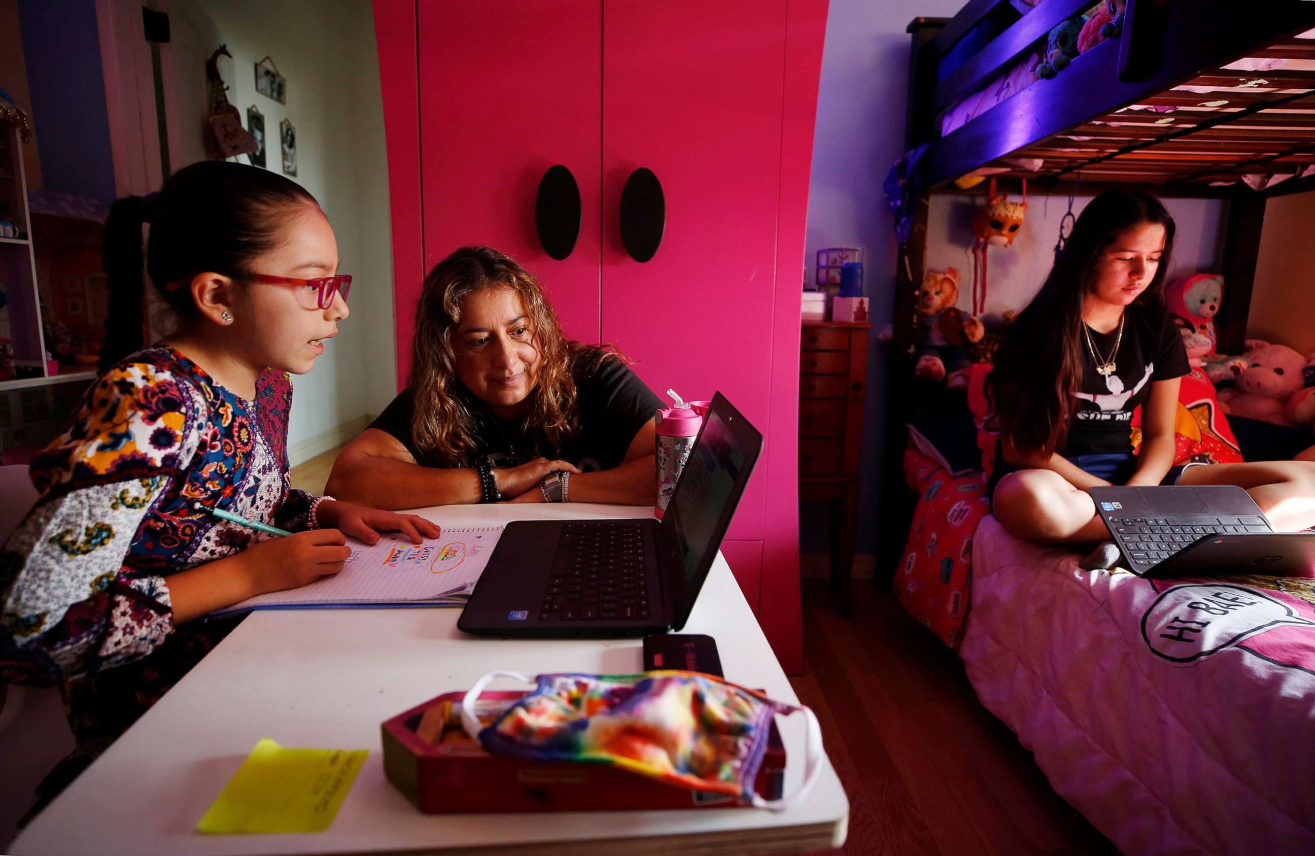 PHOTO: In this Sept. 17, 2020 file photo, children in Los Angeles use laptop computers during remote learning classes at home while their mom assists them.