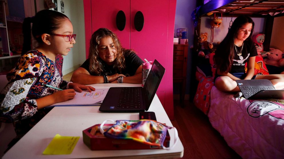 PHOTO: In this Sept. 17, 2020 file photo, children in Los Angeles use laptop computers during remote learning classes at home while their mom assists them.