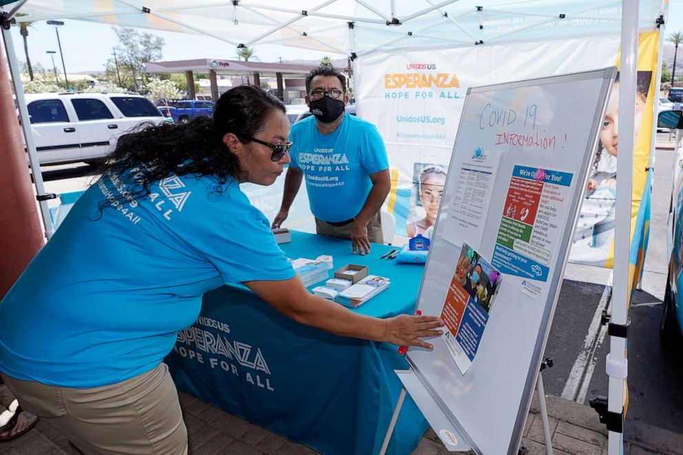 PHOTO: Sonia Lorenzana, left, and Jose Marquez, right, of UnidosUS, set up an informational tent display, increasing efforts to bring more vaccine doses into Latino neighborhoods, at a local shopping plaza in Phoenix, May 7, 2021.