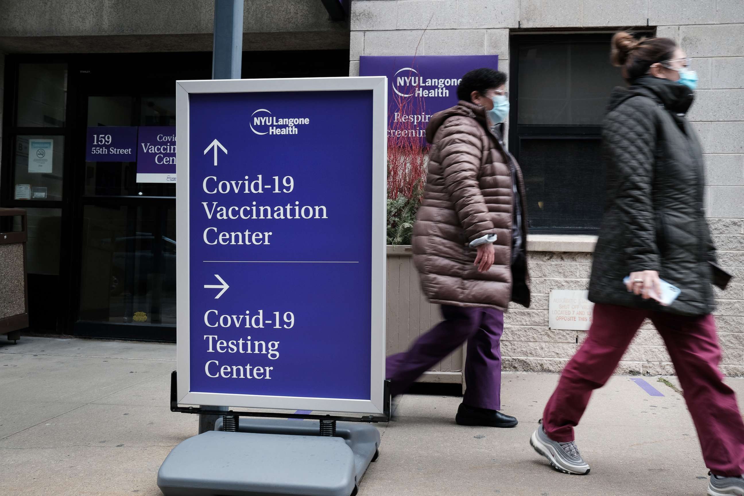 PHOTO: People walk by a sign for both a COVID-19 testing clinic and a COVID-19 vaccination location outside of a Brooklyn hospital, Jan. 27, 2021, in New York.