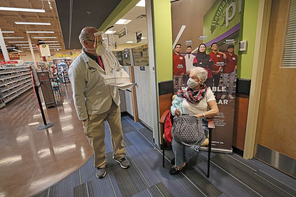 PHOTO: A woman is greeted by pharmacist John O'Sullivan at Hannaford Supermarket, as she prepares to get her coronavirus vaccine a the store's pharmacy in Taunton, Mass., Jan. 29, 2021.