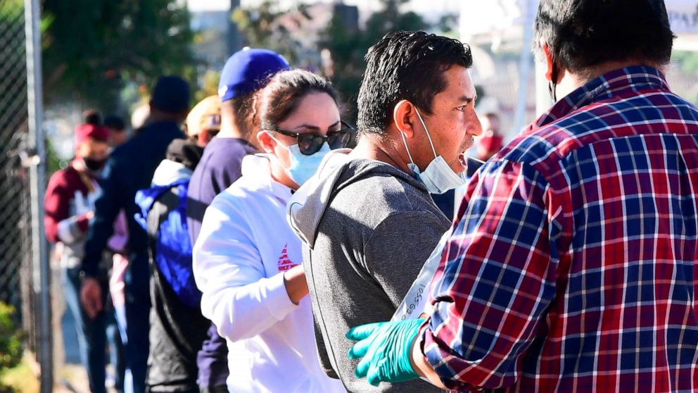 PHOTO: A man swabs his mouth as people wait in line for their COVID-19 test at a mobile pop-up testing site in Los Angeles, California, on Dec. 3, 2020.