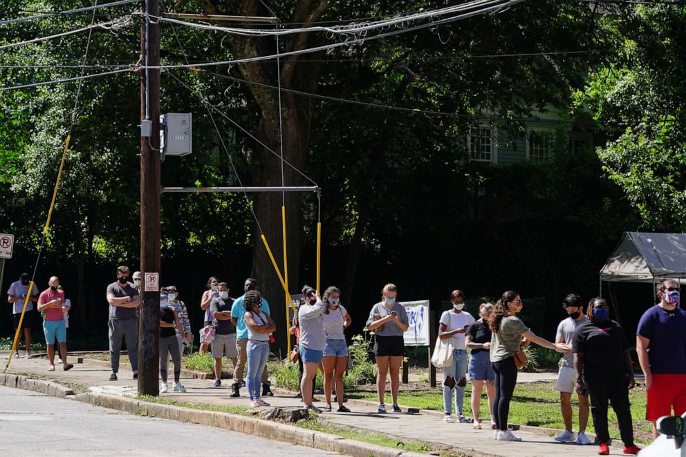 PHOTO: People stand in line to get tested for COVID-19 at a free walk-up testing site on July 11, 2020, in Atlanta.