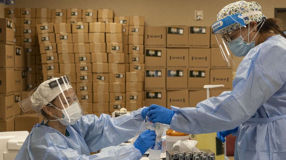 PHOTO: Medical workers from New York wearing personal protective equipments handle test samples at temporary testing site for COVID-19 in Higher Dimensions Church, July 17, 2020, in Houston.