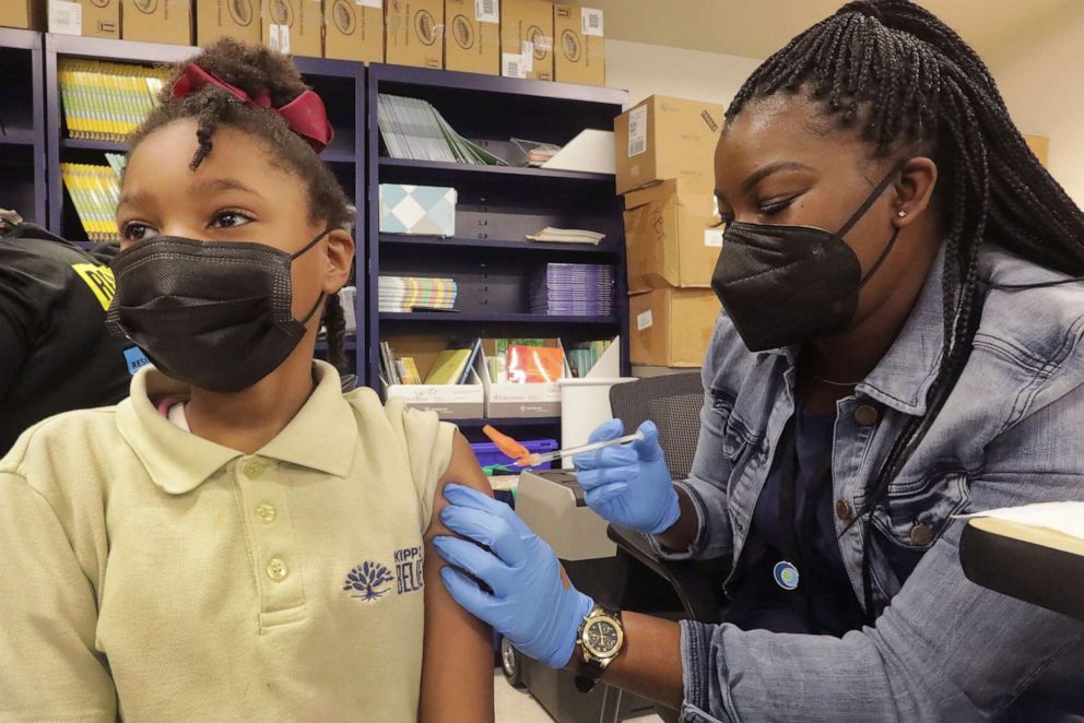 PHOTO: Third grader Nila Carey, 8, looks away as she gets her COVID-19 vaccine shot from Licensed Practical Nurse Sandra Castro at KIPP Believe Charter School in New Orleans, Jan. 25, 2022.