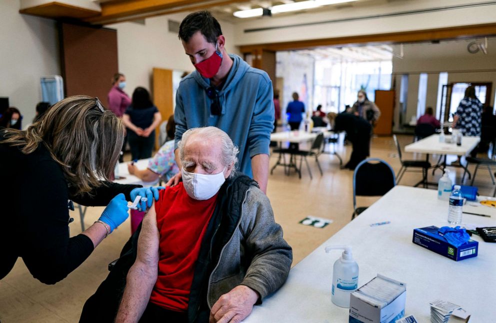 PHOTO: Thomas Cooper, 83, of Chenango Bridge, N.Y., guided by caregiver Kevin Roma, receives a COVID-19 vaccine byin Binghamton, N.Y., March 19, 2021.