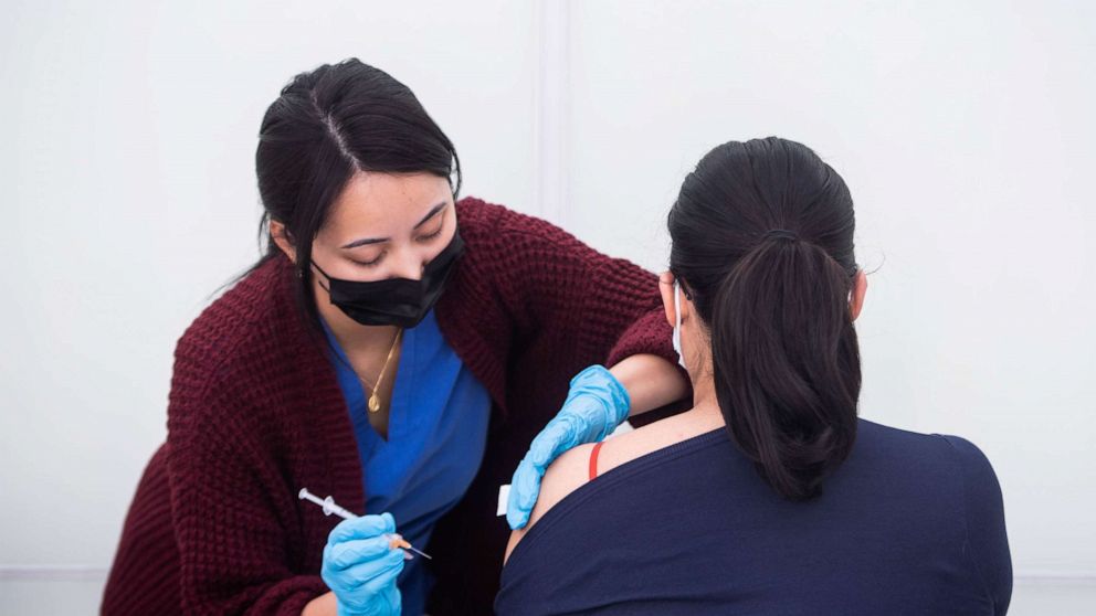 PHOTO: Charis Casino, a nurse with Fulgent COVID-19 Mobile Fleet, vaccinates a woman outside the Music Center in Los Angeles, Dec. 22, 2021. 