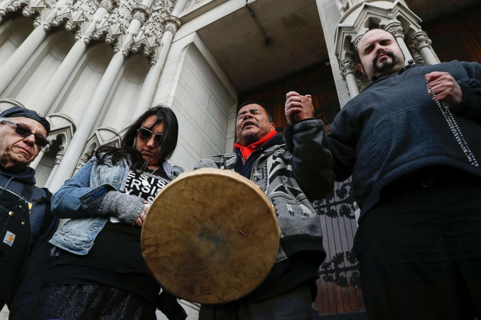 PHOTO: Native American demonstrators hold hands with parishioner Nathanial Hall, right, during a group prayer outside the Catholic Diocese of Covington, Jan. 22, 2019, in Covington, Ky.