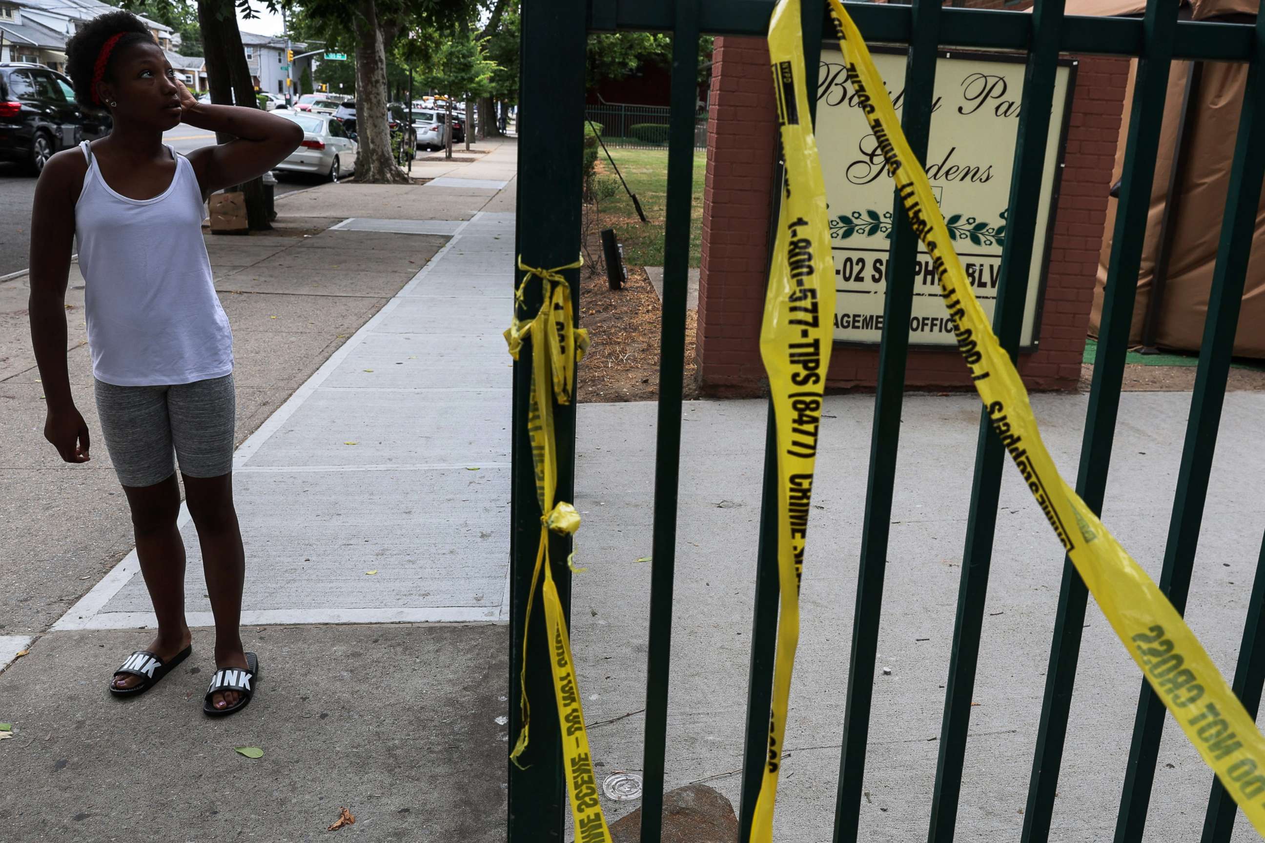 PHOTO: A woman pauses on a sidewalk, where according to police reports a shooting killed one man and injured another on Wednesday night outside an apartment building in the South Jamaica section of Queens, New York, July 7, 2022. 