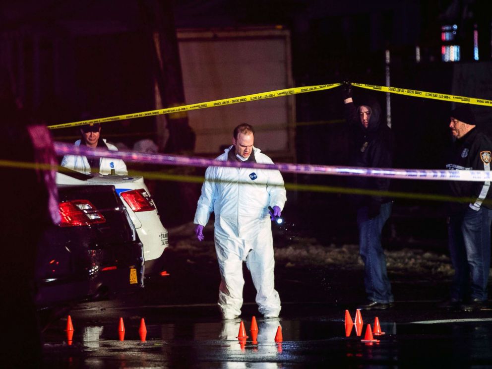 PHOTO: Investigators look over the area after a two New York City police officers were shot while responding to a robbery in the Queens borough of N.Y., Feb. 12, 2019.